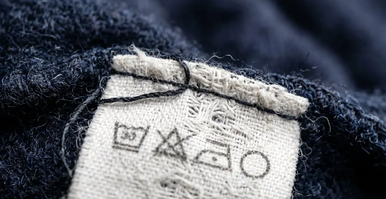 Vista macro de etiquetas de cuidado de ropa mostrando símbolos de lavado y composición del tejido