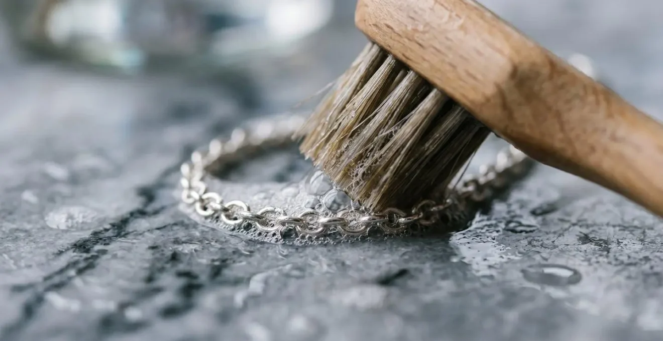 Vista macro de pendientes de plata siendo limpiados con jabón neutro