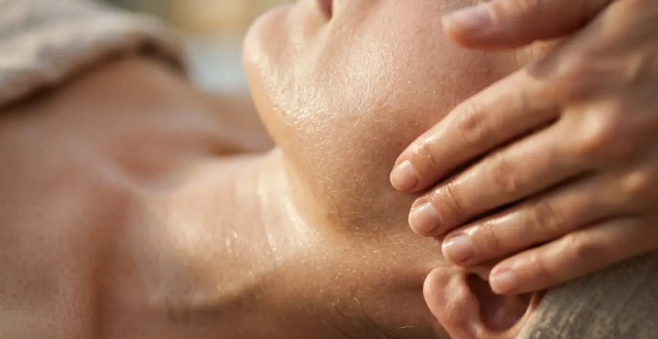 Manos realizando masaje de drenaje linfático facial con movimientos ascendentes