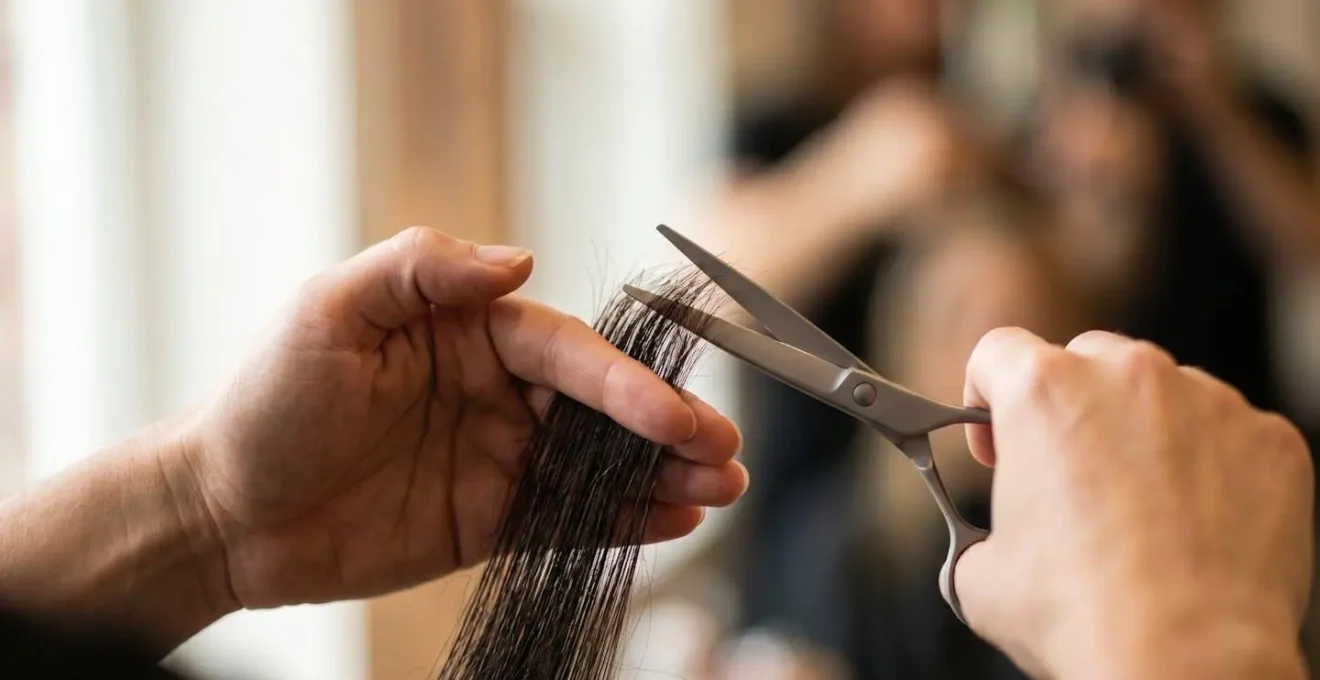 Manos de estilista realizando corte bordado selectivo en mechón de cabello