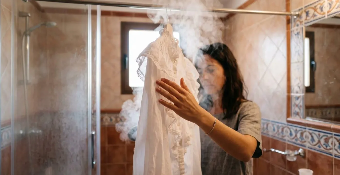 Baño de hotel con vapor y blusa colgada en la ducha